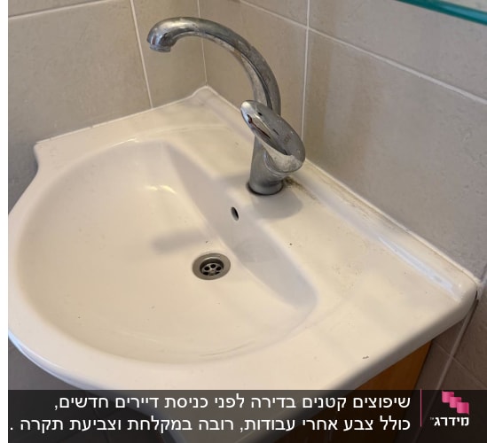כיור רחצה לבן עם איטום סיליקון בקיר ומדף זכוכית מעליו